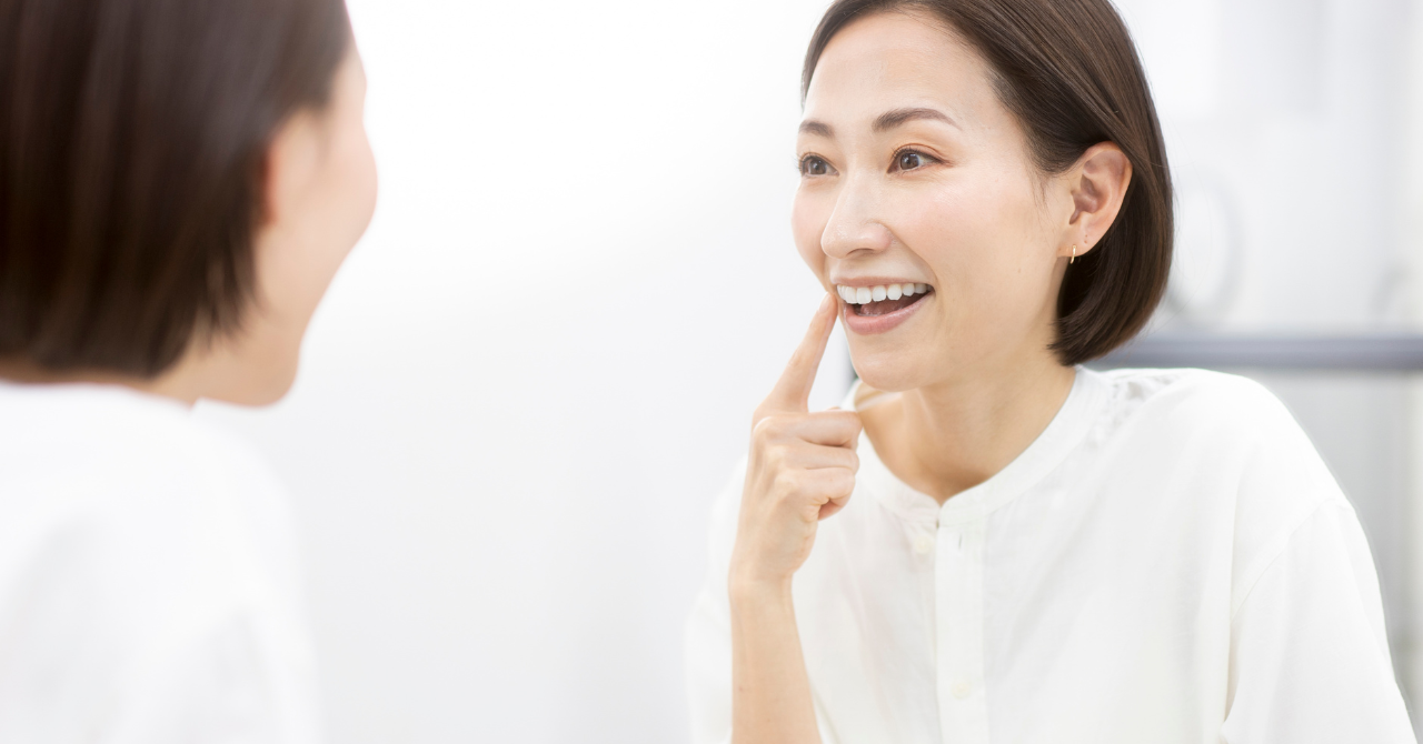 鏡を見ながら歯の色や口元の印象を確認する女性